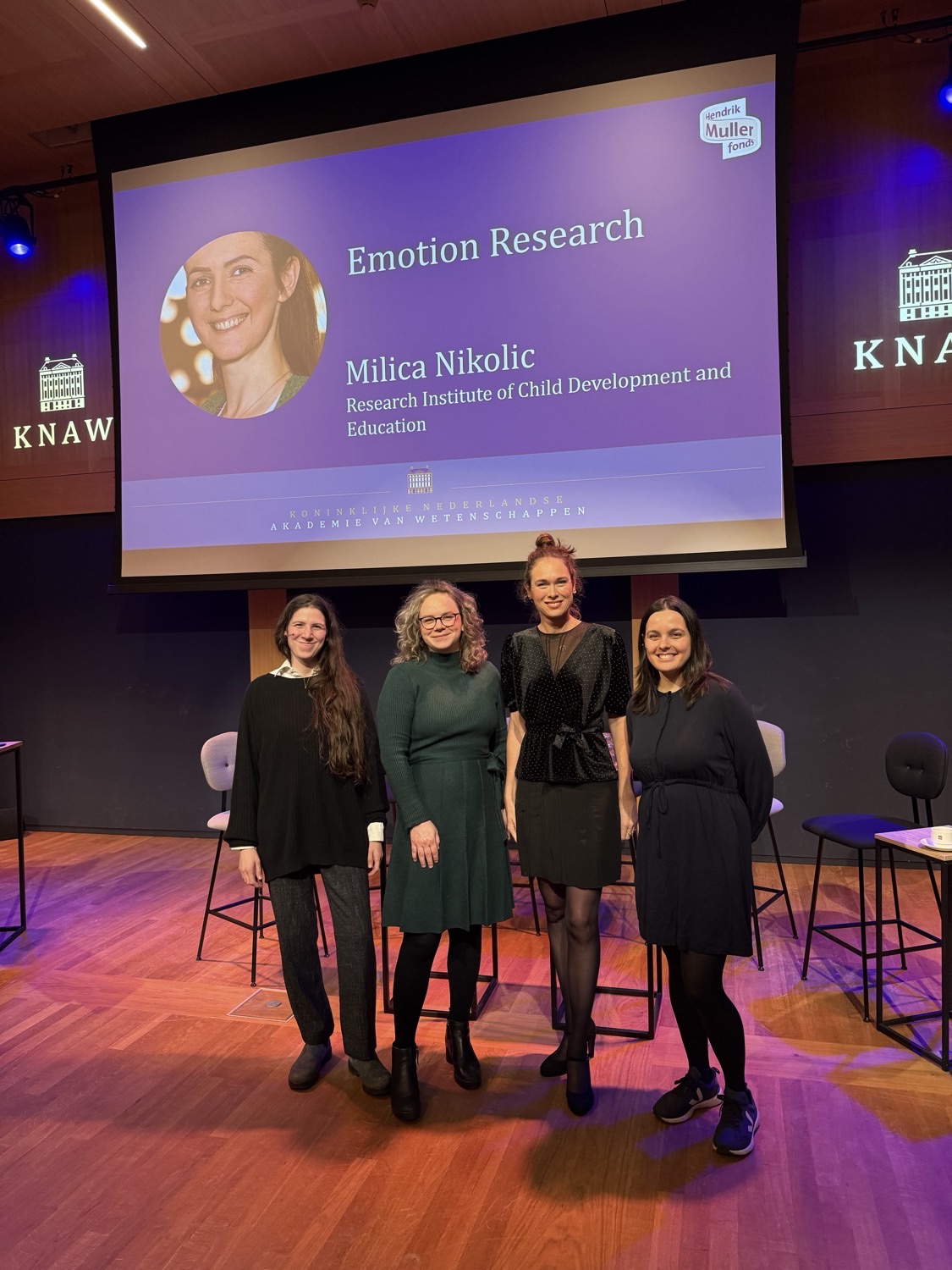 Iliana Samara with fellow panellists on stage at a KNAW symposium on mothers in science, an Emotion Research slide projected behind them.